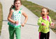 Two young girls running on sidewalk